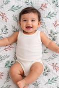 Load image into Gallery viewer, Baby boy in a white onesie lying on a leaf muslin patterned blanket
